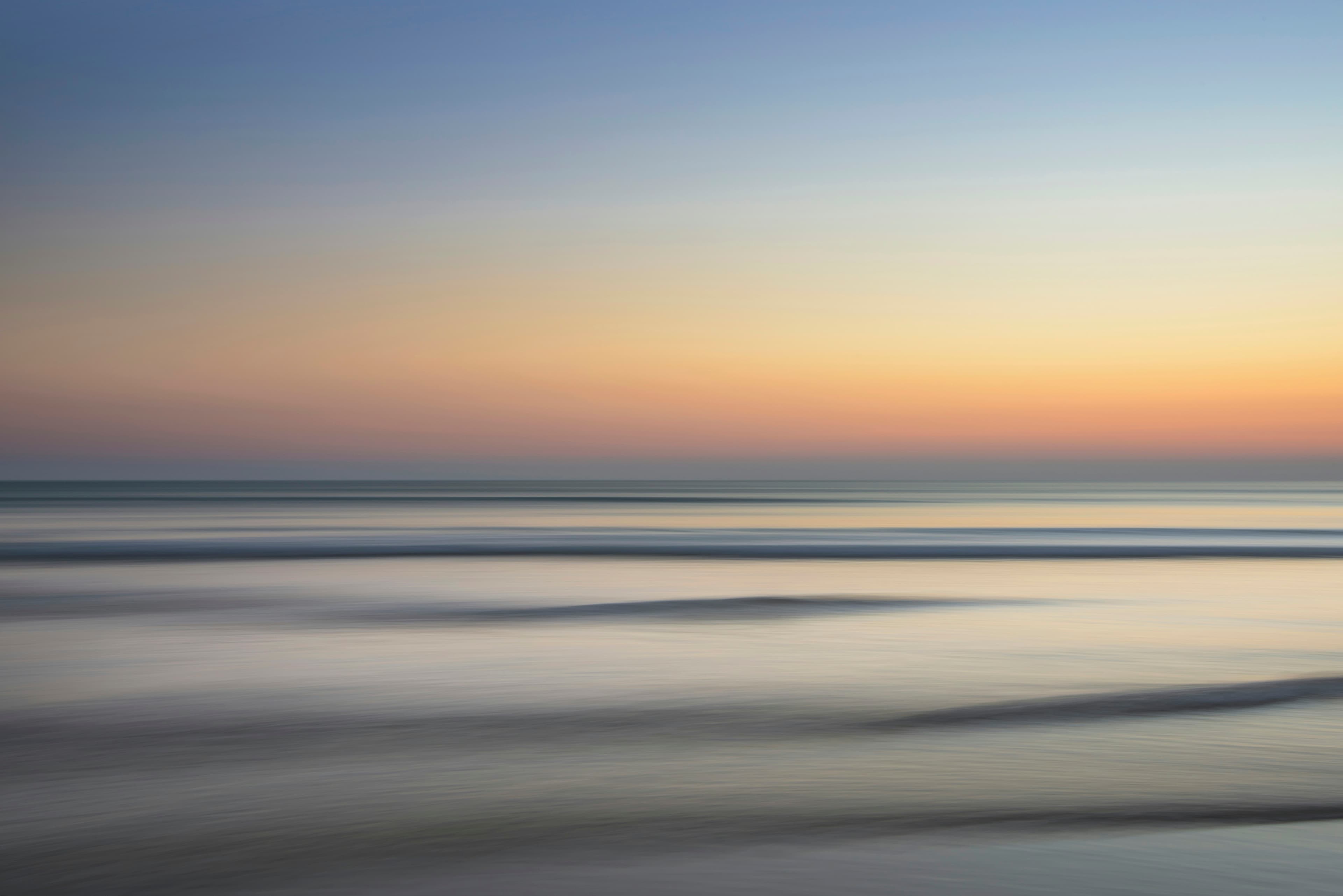 A tranquil ocean beneath a sky filled with golden, warm-toned clouds