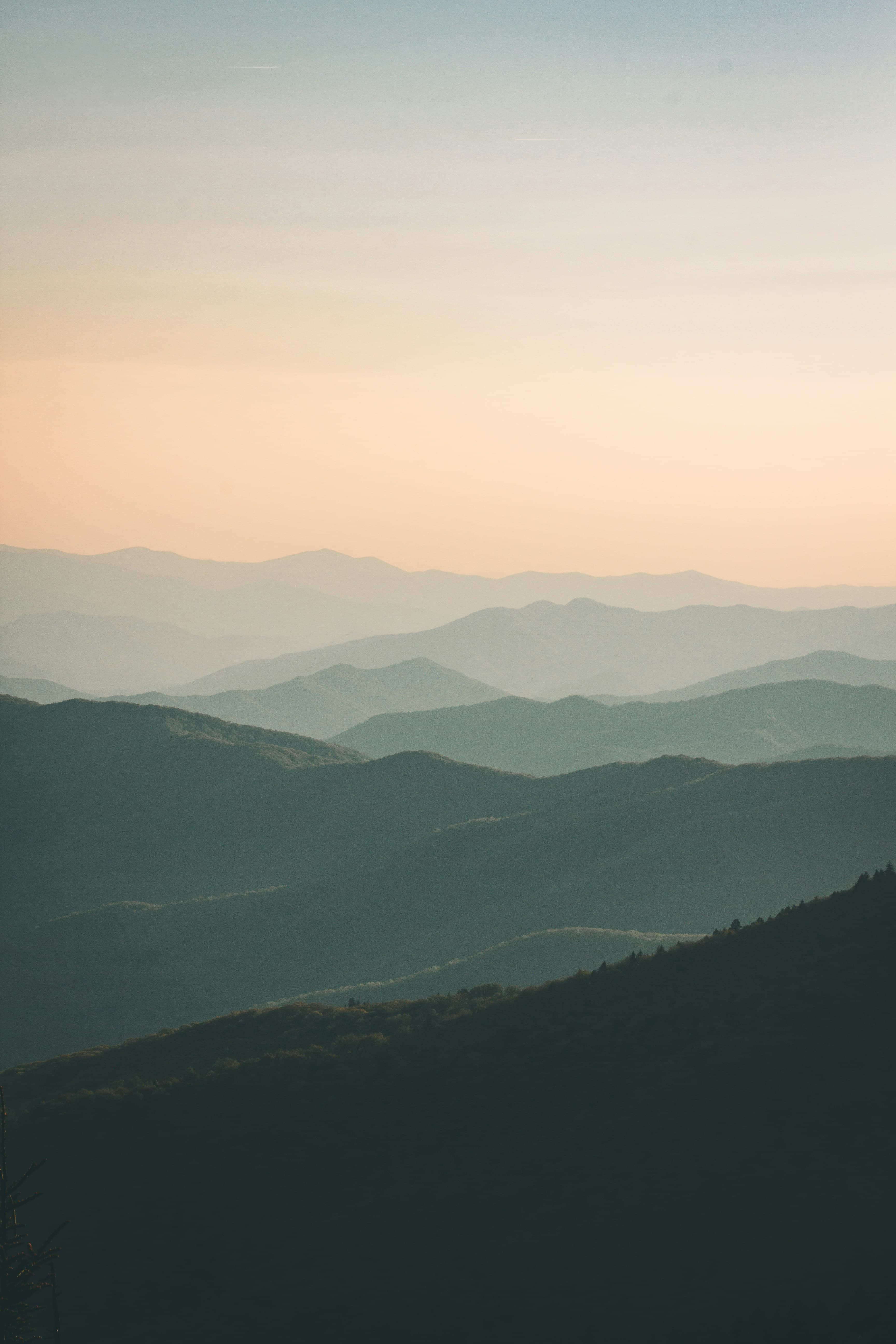 Layered mountain peaks shrouded in white mist during golden hour