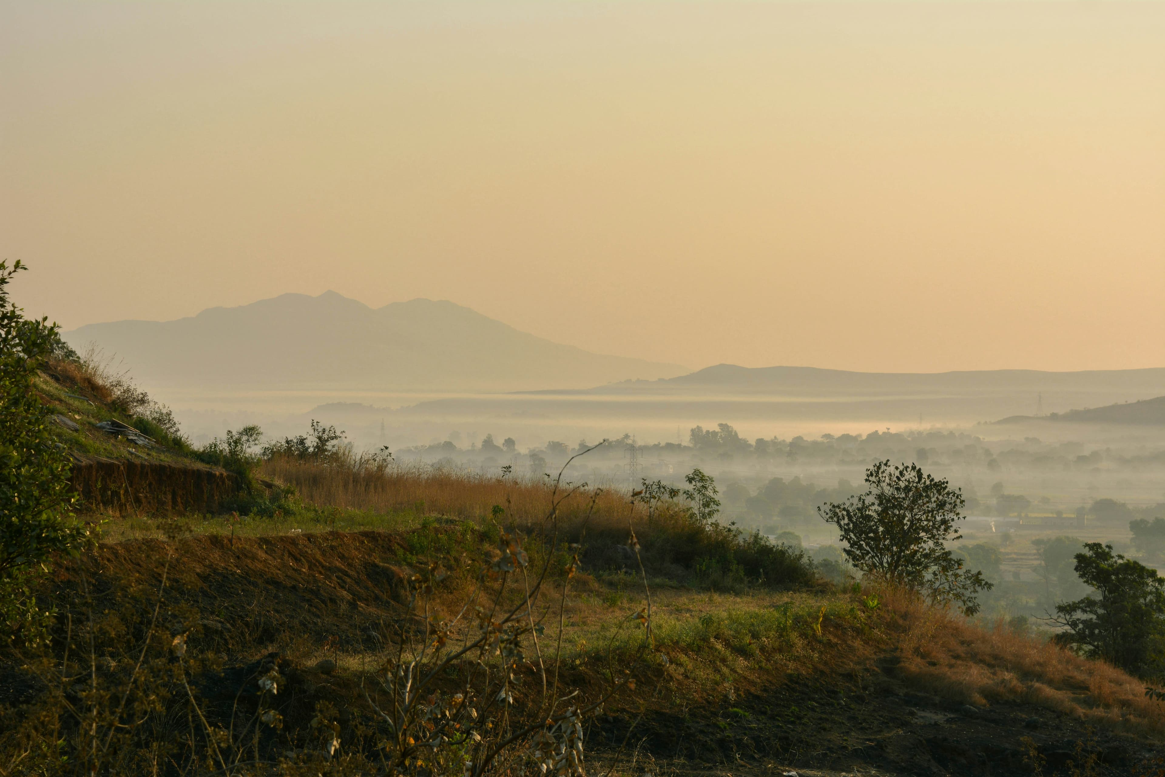 A misty valley landscape with mountain silhouettes visible through fog