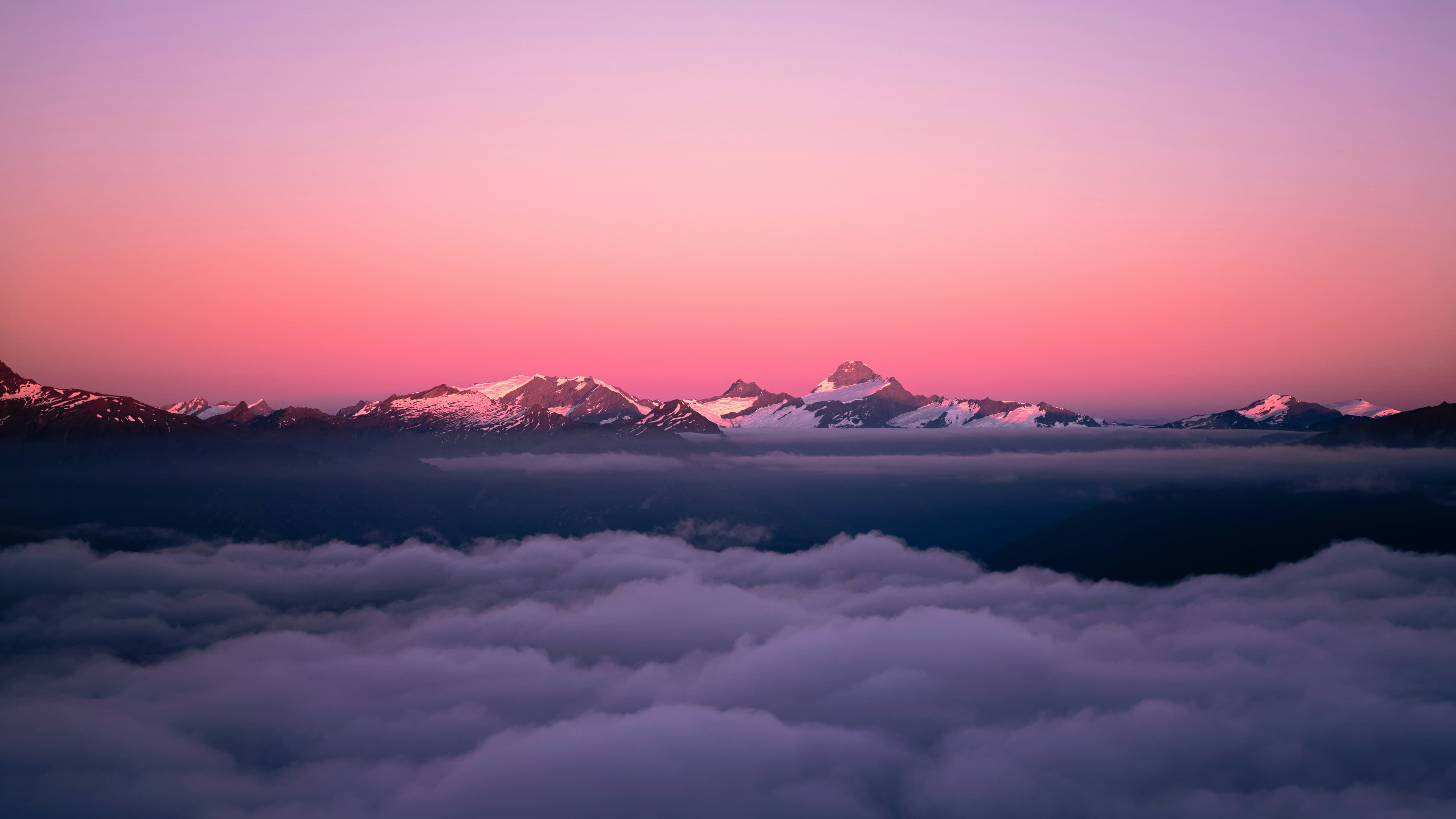 A view of a mountain range from above the clouds at sunset