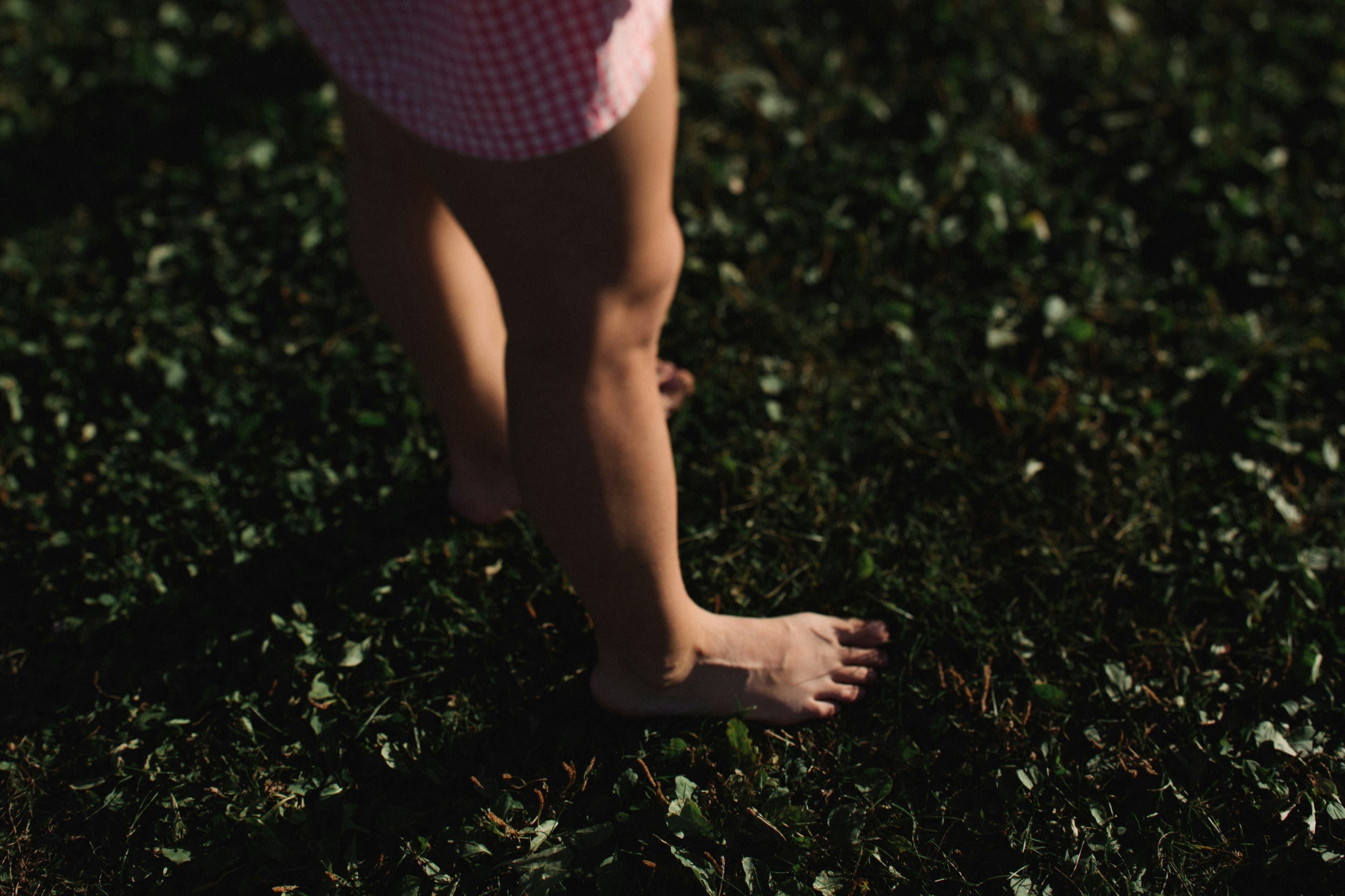 Bare feet walking across lush green grass, grounded in the present moment