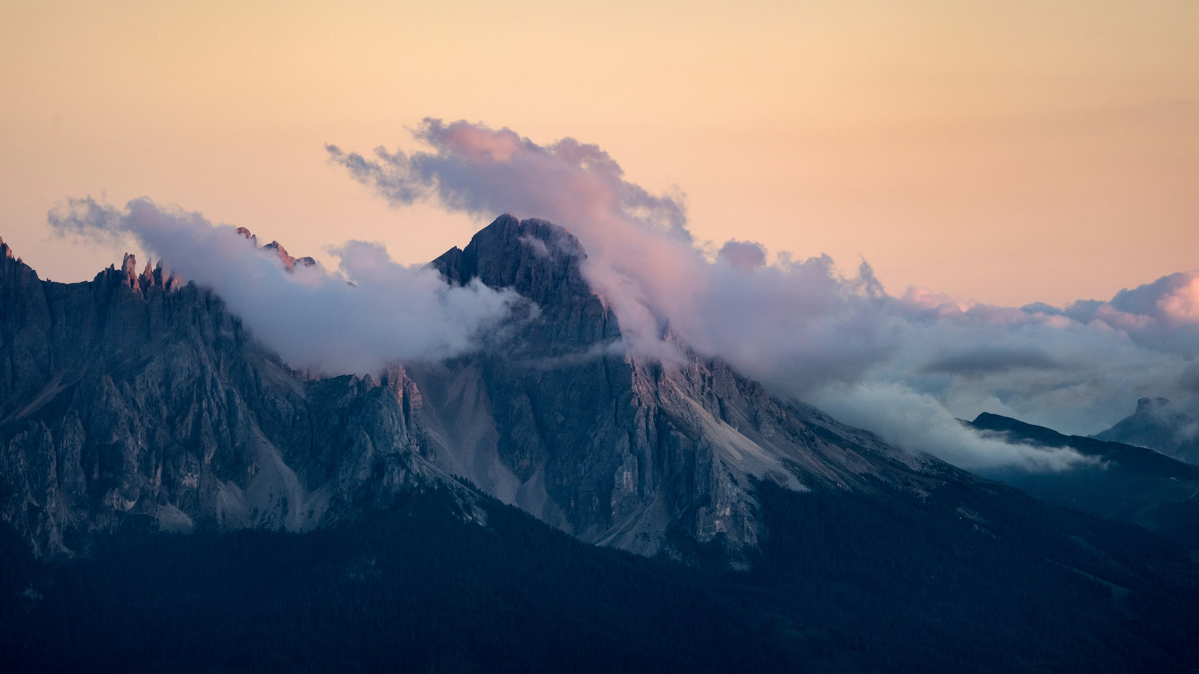 Misty mountain peaks at sunrise under a soft pastel sky